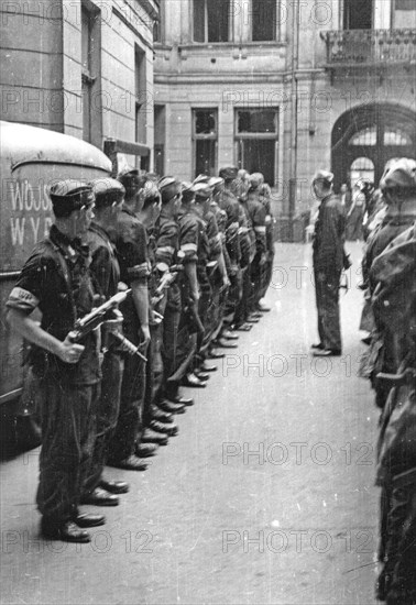 Warsaw Uprising: Debriefing of II platoon Oddzialu Oslonowego WZW „Chwaty” under command of Stefan Berent „Steb” in the courtyard of a townhouse at Bowdena Street. In the back visible a car with “WZW” on its side. ca. August 1944