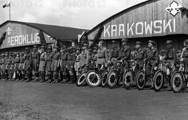 Cyclists with decorated bikes in front of the hangar of the Krakow Aeroclub at the Rakowicki airport ca. May 1, 1937