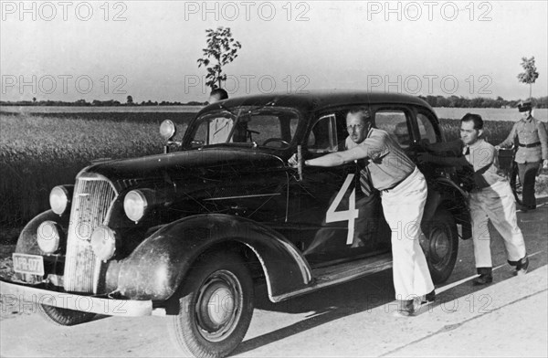 International Rally Automobile Club Poland, Grand Prix Poland 1937, new Chevrolet Master Sedan with his driver Witold Rychter and pilot Jerzy Wedrychowski. Car is not damaged. They are pushing their car to the place of start in Lomianki to avoid overhea