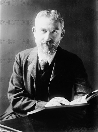 George Bernard Shaw at desk with book