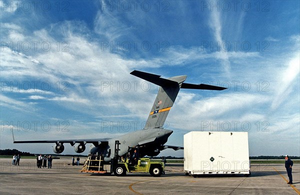 Workers prepare to tow away the large container with the Cassini orbiter from KSC’s Shuttle Landing Facility ca. 1997