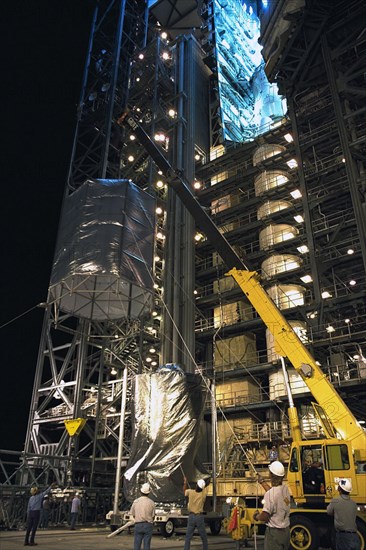 A crane lowers a protective transportation cover over the Cassini spacecraft, with its attached Huygens probe, at Launch Pad 40 at Cape Canaveral Air Station