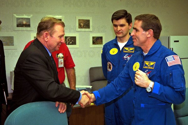 The president of the Ukraine, Leonid Kuchma, shakes hands with Payload Specialist Leonid Kadenyuk, at right, as backup Payload Specialist Yaroslav Pustovyi, both of the National Space Agency of Ukraine ca. 1997