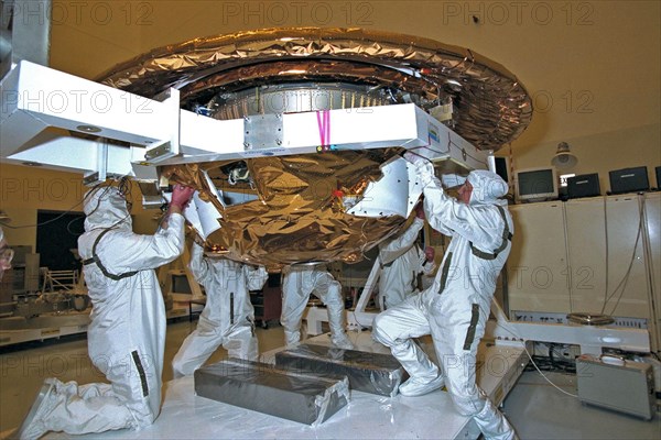 Dornier Satelliten Systeme (DSS) workers place the back cover of the Huygens probe under its front heat shield in the Payload Hazardous Servicing Facility (PHSF) at KSC ca. 1997