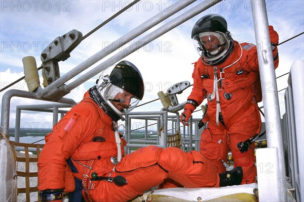 STS-85 Pilot Kent V. Rominger (left) and  Commander Curtis L. Brown, Jr. exit an emergency egress slidewire basket at the 195-foot level of Launch Pad 39A during Terminal Countdown Demonstration Test (TCDT)  activities for that mission ca. 1997