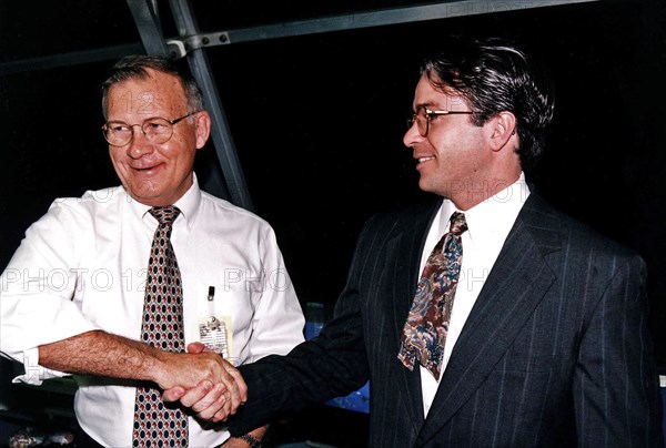 KSC Center Director Jay F. Honeycutt, at left, shakes hands with Scott Cilento, the new flow director of the Space Shuttle orbiter Discovery, in the firing room of the Launch Control Center (LCC) during the STS-82 launch of Discovery  ca. 1997