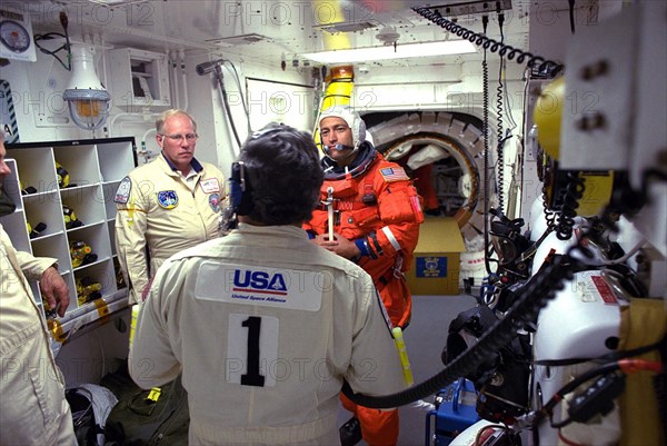 STS-84 Mission Specialist Carlos I. Noriega prepares to enter the Space Shuttle Atlantis at Launch Pad 39A with help from white room closeout crew members ca. 1997