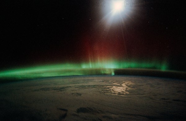 1991 - Moonlight saturates the high speed film used for auroral photography. Moon glint is visible in the open ocean and the cloud patterns are well illuminated. This frame was taken with a handheld 35mm camera from inside the Space Shuttle Discovery's cr