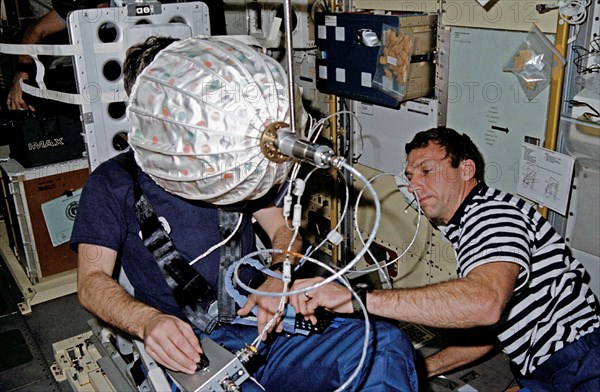 (22-30 Jan. 1992) --- Astronaut David C. Hilmers (right), STS-42 mission specialist, assists European Space Agency (ESA) payload specialist Ulf Merbold with the visual stimulator experiment on the Space Shuttle Discovery's middeck.