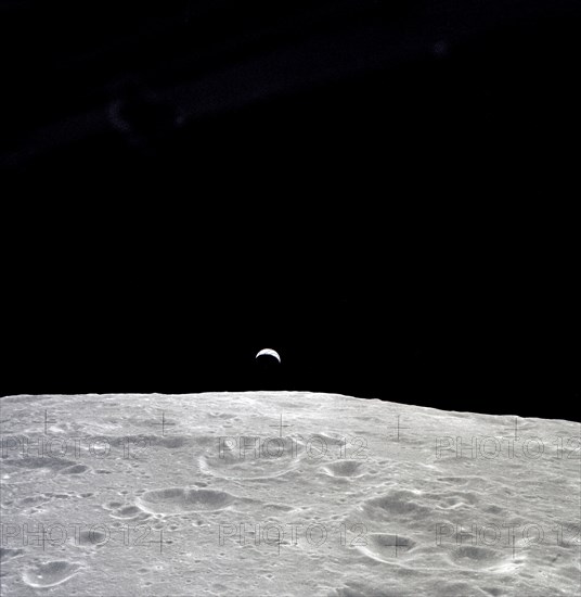 Earth rises above the lunar horizon as seen from Apollo 12 in lunar orbit