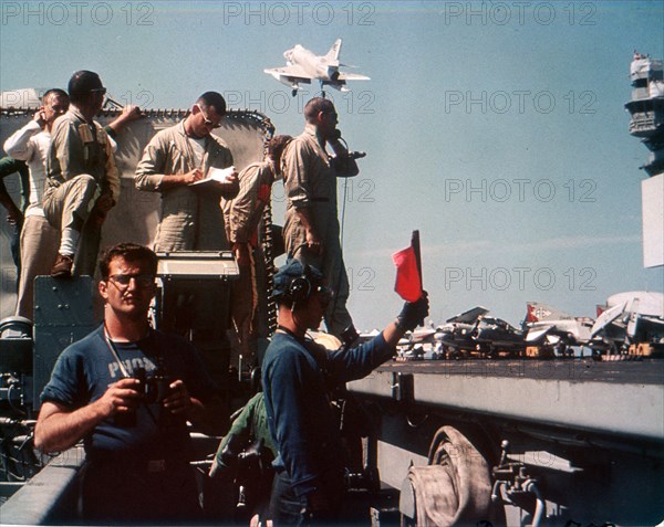 Landing Officer waves off an A-4 Skyhawk while crew prepares to receive another aboard USS ENTERPRISE. 6/65.