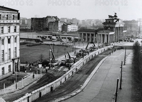 Berlin wall reinforced. Under the watchful eye of Communist police, East german workers near the Brandenburg Gate reinforce the wall dividing the city. Since erecting the wall on August 13, 1961, to stop the flow of East Germans into West Berlin, the East German Communists have added bunkers, spotlights and firing and observation posts.