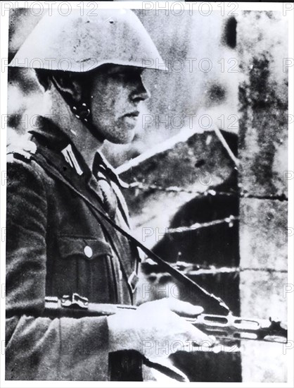 A Helmeted East German Policeman, Holding a Sten Gun Stands Guard Near a Barbed Wire Barricade at Potsdamer Platz, a Main City Square on Berlin's East-West Border