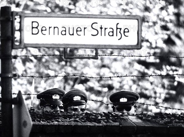 Three Communist 'VOLPO's', East German Police, Stretch to Get a Look Over a Cemetery Wall Which Happens to Run Along the West Berlin Border