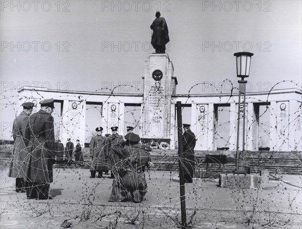 March 19, 1963 - Soviet Air Force Officers Visiting a Soldier's Memorial Under Guard from British Soldiers Behind Barbed Wire