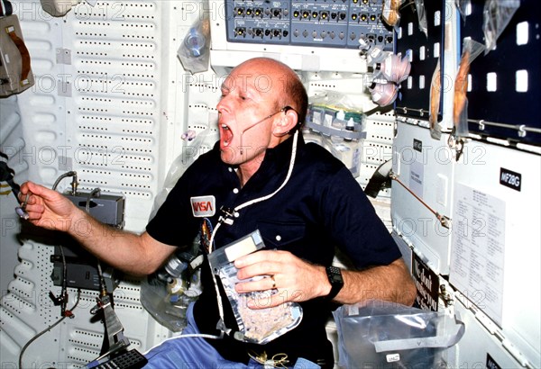 From mid-air, astronaut C. Gordon Fullerton, pilot, grabs a bite of cereal