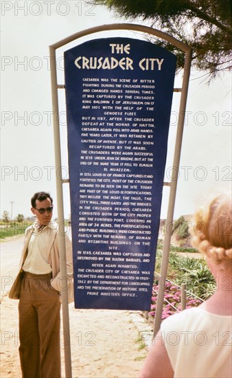 Tourists reading a sign in Caesarea about 'The Crusader City.'