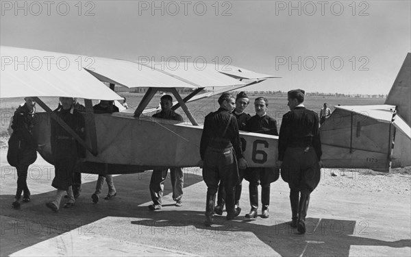 le transport d'un avion sur l'aérodrome pour l'école de vol et de vol à voile. le type date de 1939.