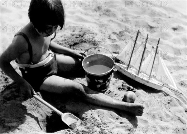 italy, seaside summer camp, little girl playing on the beach, july 1939