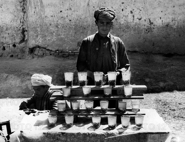 vendeur de rue vendant des sultanines et de l'eau sucrée à kaboul, 1960