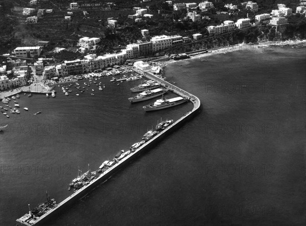 italia, campania, isola di capri, veduta aerea di marina grande con il molo, 1964