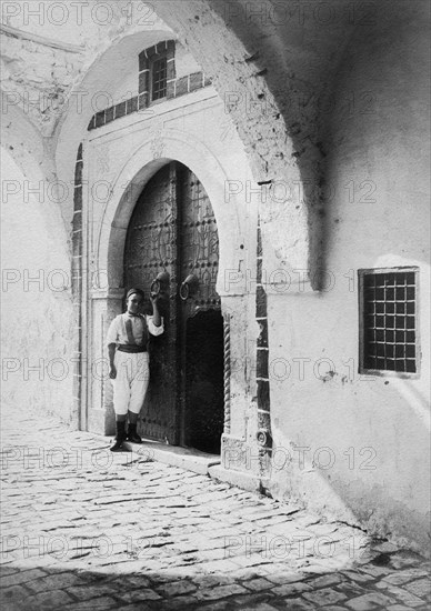 afrique, tunisie, île de djerba, un garçon à l'entrée de sa maison, 1910 1920