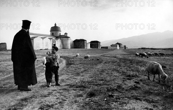 europa, italie, calabre, frascineto, moine basilien avec enfant près de l'église, 1965
