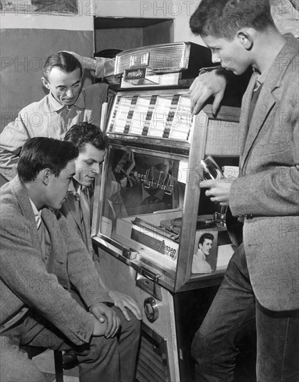 jeunes gens autour d'un juke box écoutant un disque, 1960