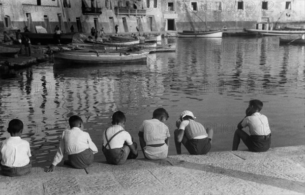 toscane, livourne, portoferraio, enfants assis sur le bord de la jetée, 1930