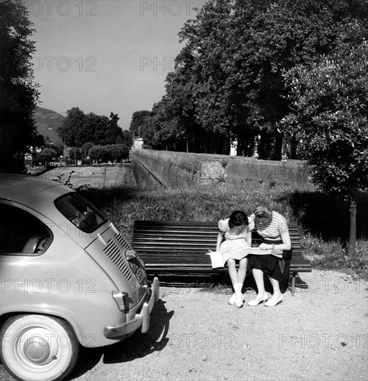 touristes sur un banc consultant une carte, 1956