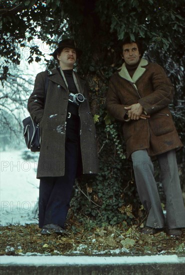 Two men posing under a tree.