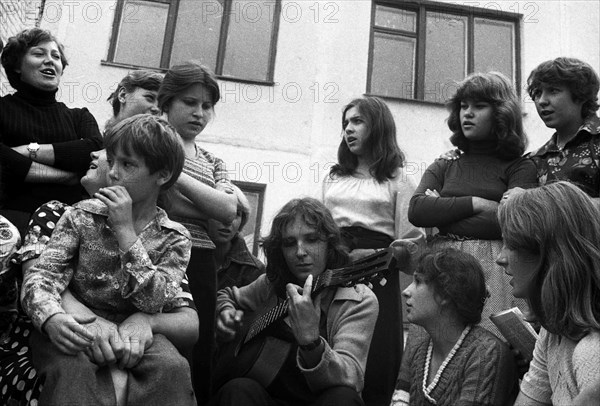 Youth with a guitar sings in the school yard.