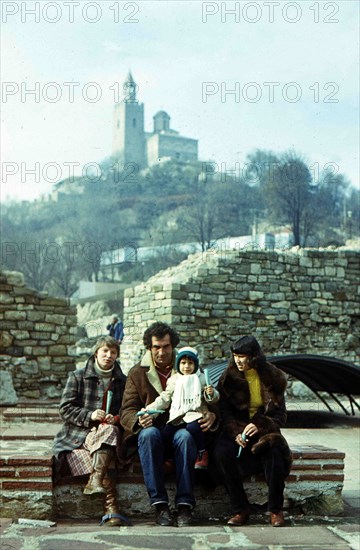 Tourists sit on the bench against Tsarevets Hill.