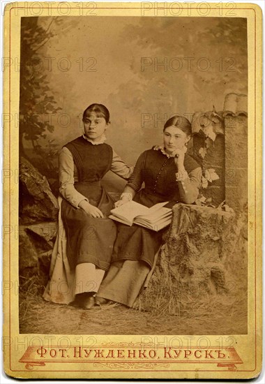 Two girls with a book in her lap.
