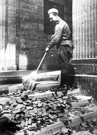 Russian Soldier Cleans Nazi Propaganda Material.