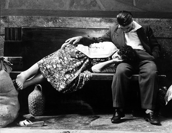 Couple on a bench in the central station of Milan, Italy 60's