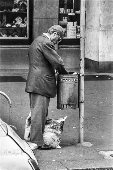 Elderly man looking in a trashcan, near central station in milan, italy