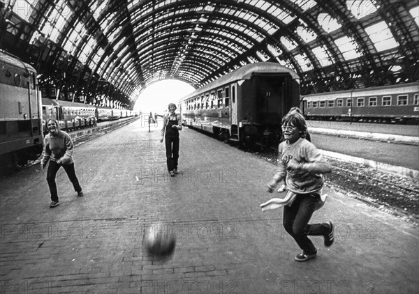 Three teen playing football at central station in milan, 70's