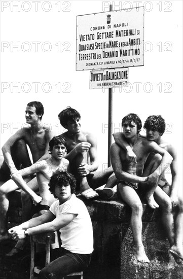 Young man at naples's harbour, no swimming sign, 70's