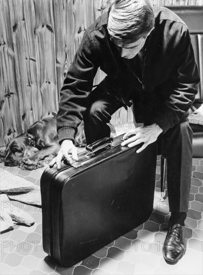 A man  closes a briefcase, 1965