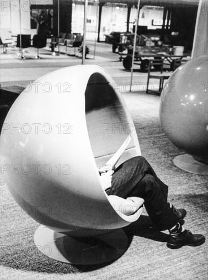 A man sitting on the ball chair by Eero Aarnio at the fair in Milan. Italy. 1967