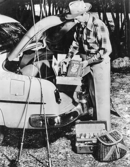 A fisherman organizes the luggage van of his car, 1962