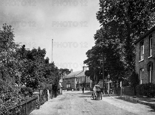 Wretham in Suffolk a typical street with a man on a cart and a man on a bicycle.