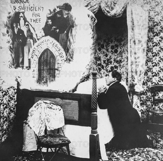 Man on knees at bedside praying to God.