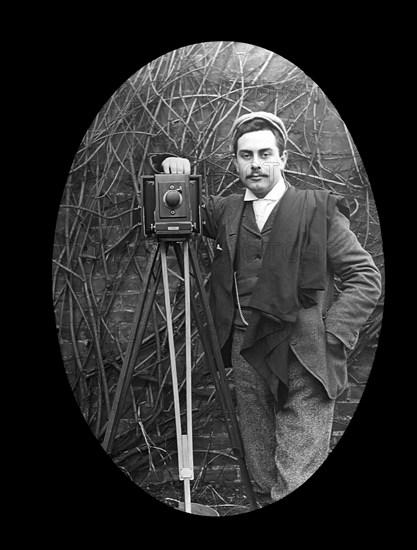 A photographer and tripod posing for a photograph in 1897.