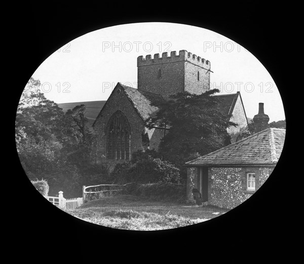 A village church and cottage with disabled three wheel carriage in the garden.