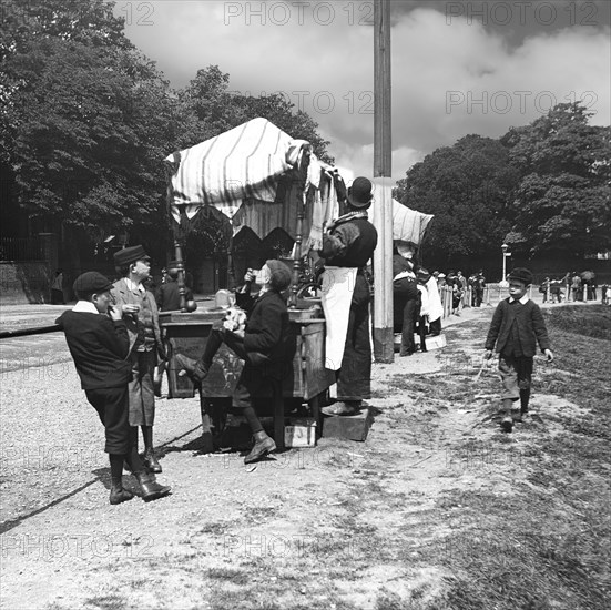 A view of children and people at a market in the park, perhaps an exhibition.