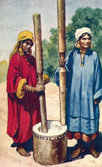 Indian women pounding rice.