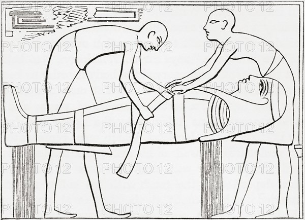Ancient Egyptians swathing or wrapping bandages round a mummy.