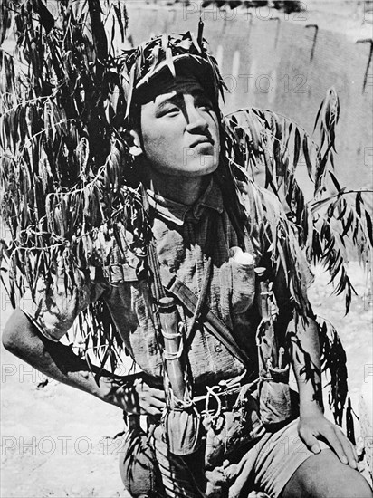 In the Sino-Japanese war a young chinese soldier armed with grenades and camouflaged outside the Citadel of Tungkwan on the Yellow river.